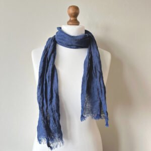 Dark blue small linen scarf tied around a white mannequin neck, showing a lightweight woven texture and fringe edges.