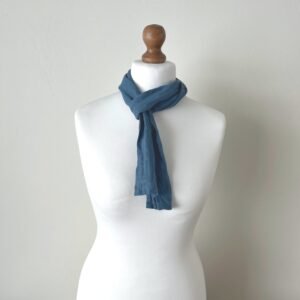 Small tie-like blue scarf made of softened linen fabric, knotted on a white mannequin.