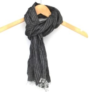 Knotted small black and grey vertical striped linen scarf with frayed edges hanging on a wooden hanger against a white background.