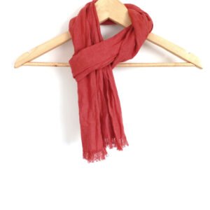 Small burnt orange handmade linen scarf with frayed edges hanging on a wooden hanger against a white background