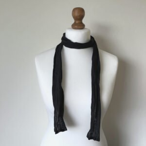Black skinny scarf made of softened linen fabric, displayed on a white mannequin. The scarf is thin, with a simple design.