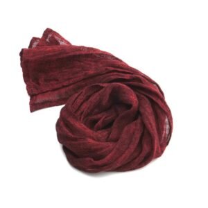 Small dark red scarf made of lightweight gauze linen fabric coiled on a white background.