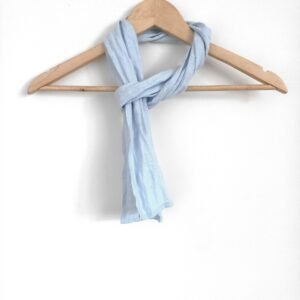 A skinny light blue softened linen scarf hanging on a wooden hanger. The scarf is thin, with a simple design.